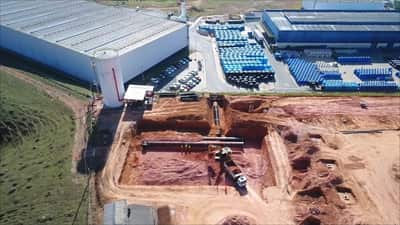 Vista aérea do galpão industrial do Brazilian Business Park com a frente de terraplenagem e drenagem em execução ao lado
