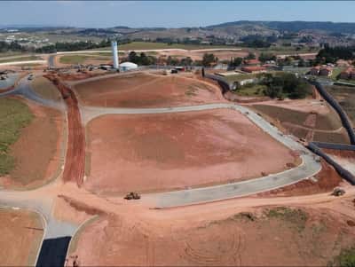 Vista aérea da terraplenagem do loteamento, com plataformas niveladas, caixa viária em execução e reservatório de água ao fundo